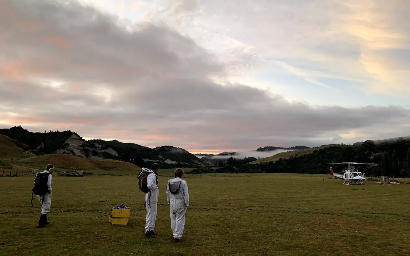 Beekeeping team and helicopter in a remote field before apiary work